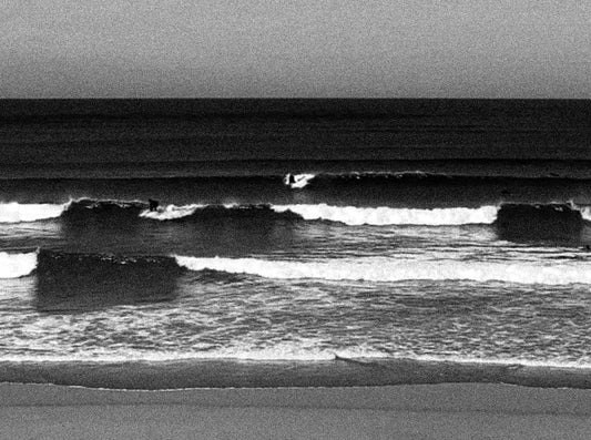 Surfer at Fistral Beach, Newquay, with waves and overcast sky in the background