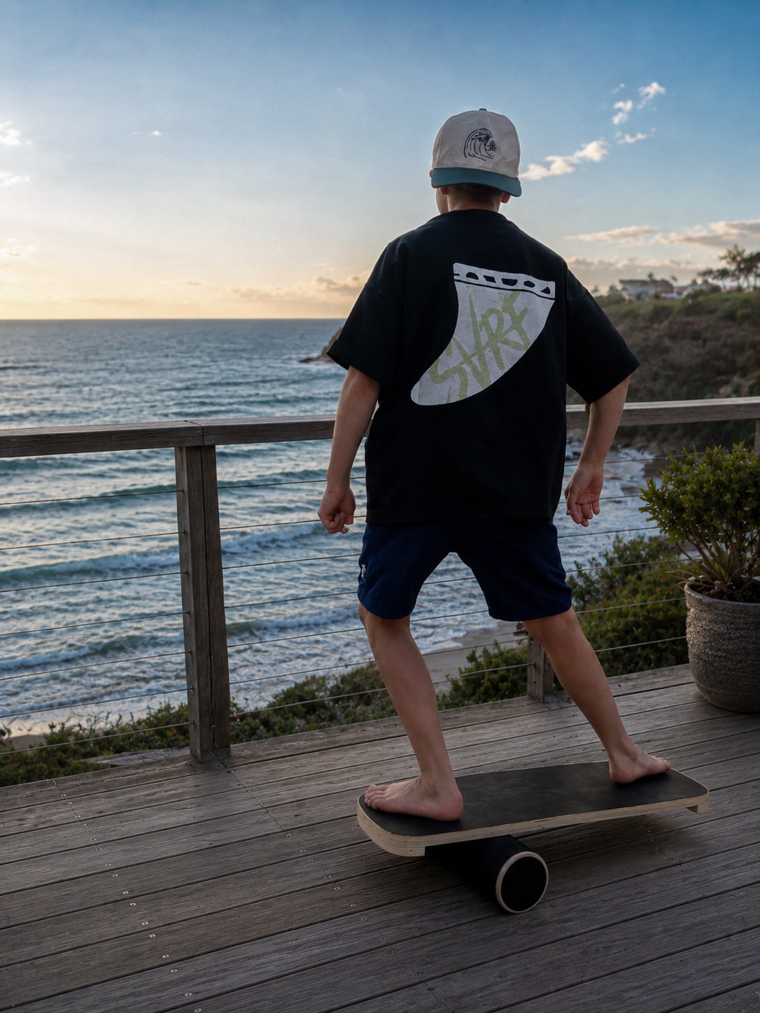 Wearing the SVRF Bennett Grom Tee, skating along a seafront boardwalk